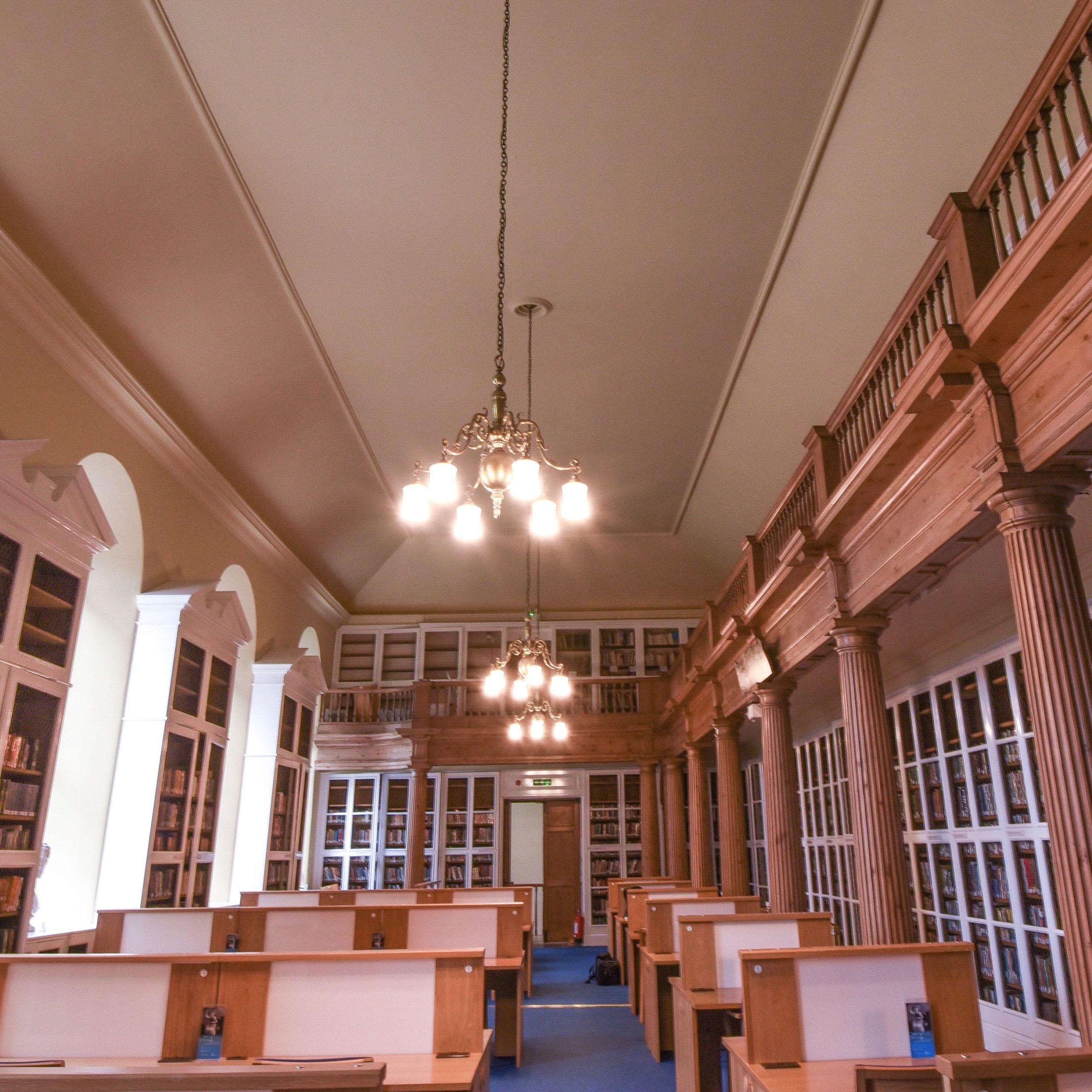 A library with desks in the middle and a balcony